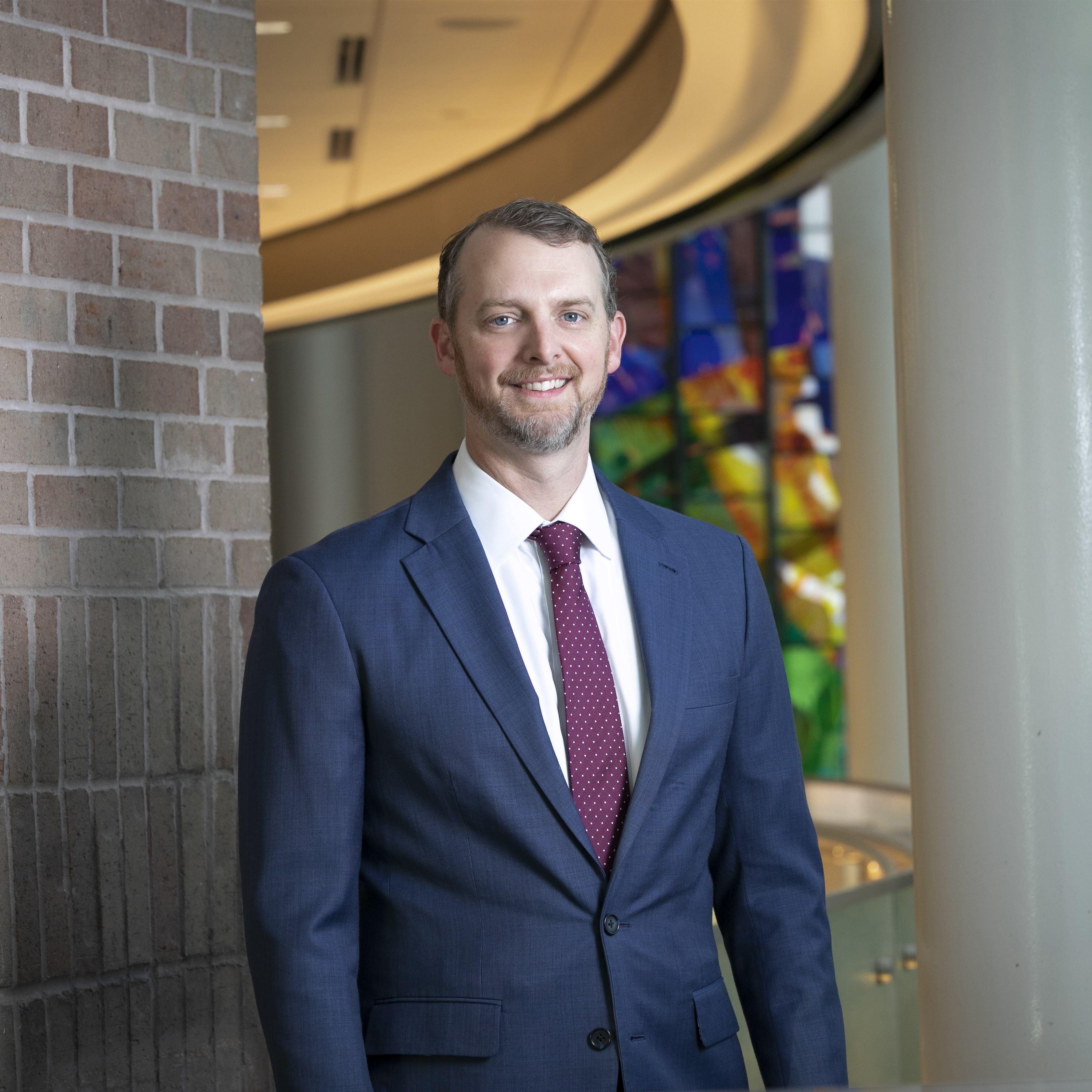 Jonas Fontenot wears a dark suit for a headshot.