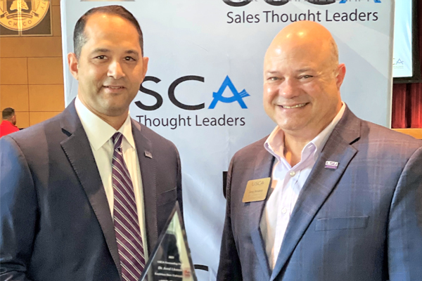 Jared Llorens hold award while standing next to Greg Accardo both men are wearing suits. Jared Llorens hold award while standing next to Greg Accardo both men are wearing suits.